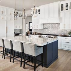 a large kitchen with white cabinets and marble counter tops, along with bar stools