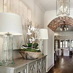 an entry way with two lamps and a vase filled with flowers on top of a table