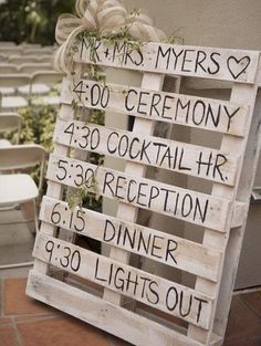 a wooden sign that has been decorated with wedding date and names on it, in front of some chairs