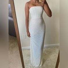 a woman taking a selfie in front of a mirror wearing a white strapless dress