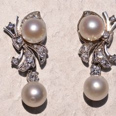 The 182nd Street: Hollywood Glam Era Pearl And Diamond Dangler Earrings. The Earrings Each Feature An Akoya Cultured Pearl Dangling With A Round Brilliant Cut Natural Diamond At The Bottom. Above Is A Bow Motif Set With Transitional Round Brilliant Cut Natural Diamonds With An Additional Akoya Pearl. The Diamonds Have An Approximate Total Weight By Measurement Of 0.52 Carats. The Pearls Have A Measurement Of 7.5 Millimeters. The Earrings Are Finished With Posts And Push Style Backs And Are Crafted In 14 Karat White Gold, Measuring Just Under 1.25 Inches In Total Length. Luxury Platinum Pearl Earrings For Formal Occasions, Classic Platinum Pearl Earrings For Formal Occasions, Classic White Gold Pearl Earrings, White Gold Clip-on Diamond Earrings For Formal Events, Luxury Platinum Pearl Earrings For Wedding, Luxury White Clip-on Diamond Earrings, Elegant Platinum Pearl Earrings For Formal Occasions, Formal White Gold Clip-on Diamond Earrings, Vintage White Diamond Earrings For Formal Occasions