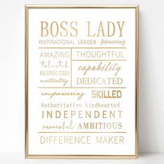 a gold framed print with the words boss lady in different languages on it, against a white wall