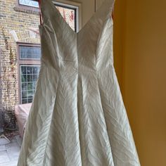 a white dress hanging up in front of a window