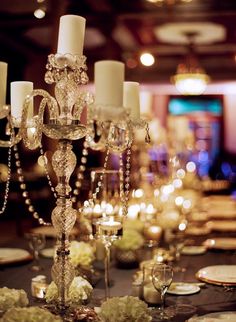 an elegant table setting with candles and flowers on the centerpieces is ready to be served