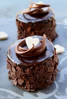 two cakes with chocolate frosting and white hearts on top are sitting on a table