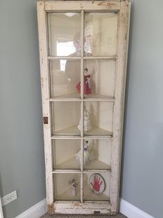 an old white cabinet with glass doors in the corner