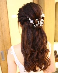 a woman with long brown hair wearing a white dress and flowers in her hair is looking at herself in the mirror