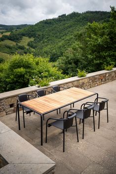 an outdoor table and chairs on a patio overlooking the valley in the distance with trees