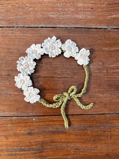 crocheted bracelet with white flowers on a wooden surface, tied in a knot