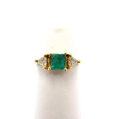 A lovely gemstone ring you're sure to make a statement with, no one else will have a piece just like this. Set in 14k yellow gold, the ring is a traditional 3-stone, featuring a square cut jungle green emerald and two lovely trilliant cut diamonds on the sides. The center stone measures 5.6mm x 5.1mm, approximately half a carat in size.  The two side diamonds are both trilliant cut, measuring .20 carats total weight together. This is a brand new piece for sale in our shop.  It is a stock size 6 1/2, a hair shy really, and can be easily re-sized at any jewelry shop. Luxury Emerald Gemstones With Accent Stones, Luxury Trillion-cut Emerald Ring, Luxury Three Stone Gemstones For Anniversary, Oval Three Stone Emerald Ring In Yellow Gold, Luxury Emerald Gemstones In Yellow Gold, Luxury Yellow Gold Emerald Gemstones, Elegant Emerald Cut Three Stone Birthstone Ring, Diamond Jewelry With Center Stone For May Birthstone, Formal Trillion Cut Three Stone Jewelry