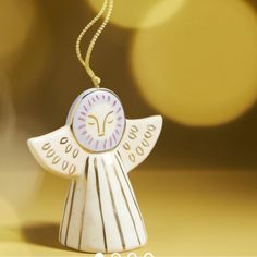 a ceramic angel ornament hanging from a gold colored string with lights in the background