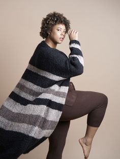 a woman is posing with her leg up in the air while wearing a black and white striped sweater