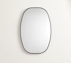 an oval mirror hanging on the wall with black trim around it's edges and bottom edge