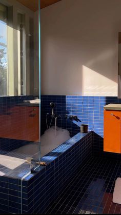 a bathroom with blue tiles and orange cabinets