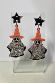 Make a spooky statement with these Halloween Glitter Ghost Earrings! These adorable drop earrings feature glittery ghosts wearing witch hats, topped off with a star stud. Perfect for adding a touch of fun to your holiday outfit. (No tricks, just treat yourself with these earrings!) Approx. Size: 1" X 2.38 drop Witchy Halloween Party Earrings, Witch Hats, Ghost Earrings, Glitter Earrings, Holiday Outfit, Star Studs, Top Graphic Tees, Love Bracelets, Earrings Collection