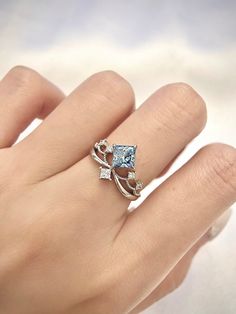 a woman's hand with a blue and white diamond ring on top of it