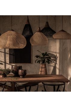 a dining room table with four hanging lights above it and plants in pots on the table