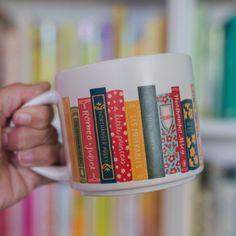 a person holding a coffee cup with books on it