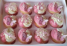 a box filled with pink cupcakes covered in white frosting and butterfly decorations