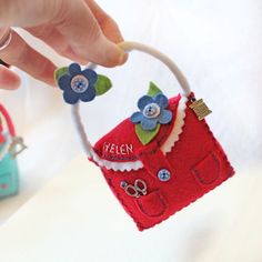 a hand holding a small red purse with blue flowers on it and the name ellen