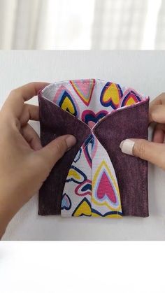 two hands are holding an origami folded piece of cloth with hearts on it