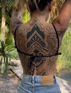 the back of a woman's body with tattoos on it