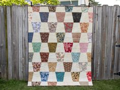 a multicolored quilt hanging on a wooden fence