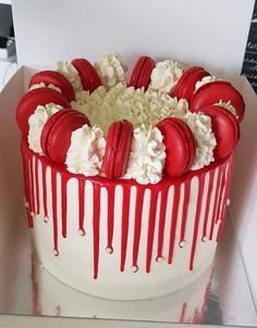 a white cake with red and white icing on it's top is sitting in a box