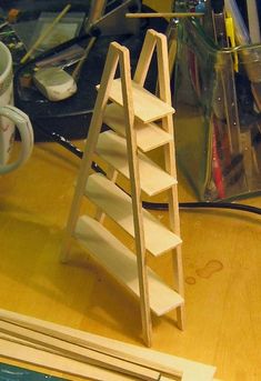 a wooden shelf sitting on top of a table next to a cup and pencils