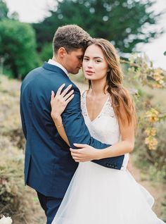 a bride and groom embracing each other in the woods