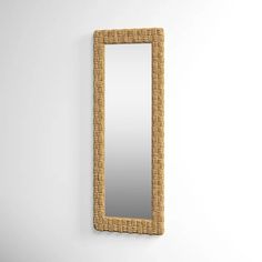 a mirror that is on the wall next to a white wall with a rattan frame