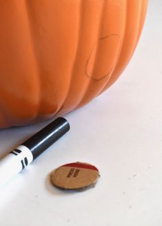 an orange pumpkin sitting on top of a table next to a marker