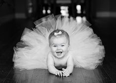 a baby wearing a blue tutu laying on top of a wooden floor