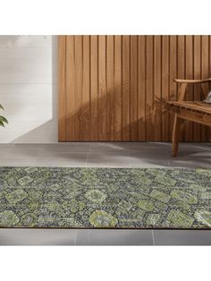 an area rug is shown in front of a wooden wall and bench with potted plant