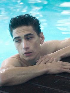 a young man leaning on the edge of a swimming pool with his arms crossed and eyes closed