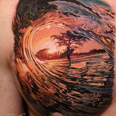 a man with a tattoo on his back holding a surfboard in front of an ocean wave