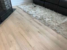 a living room with a black couch and white rug on the floor next to a fireplace