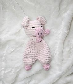 a pink crocheted stuffed animal laying on top of a white blanket