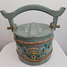 an old wooden basket with painted flowers on the outside and inside, sitting on a white surface