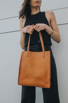 Tall market tote crafted in pebbled vegetable tanned leather and an unlined interior. The sleek minimal design makes it a great everyday bag for work, school or a visit to the farmers market. It features reinforced bottom support and large interior pocket to keep your keys and phone close by. Photo by Ashlee  Huff #bags #handbag #tote  #camel #minimal #leather   #vegetabletanned  #totebag Simple Solid Leather Shoulder Bag, Casual Everyday Bag With Smooth Grain, Minimalist Leather Bag For Everyday Use, Minimalist Smooth Grain Shoulder Bag For Shopping, Chic Everyday Shoulder Bag In Vegetable Tanned Leather, Minimalist Workwear Shoulder Bag With Leather Lining, Minimalist Shoulder Bag With Leather Lining For Work, Everyday Casual Shoulder Bag With Smooth Grain, Minimalist Leather-lined Shoulder Bag For Work