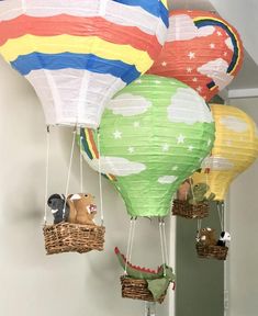 several colorful hot air balloons in the shape of animals hanging from strings and wicker baskets