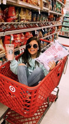 a woman is sitting in a shopping cart and reading the paper she's holding