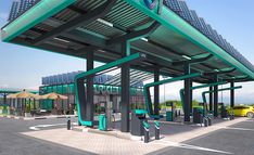 an empty gas station with cars parked in the parking lot and umbrellas on the roof