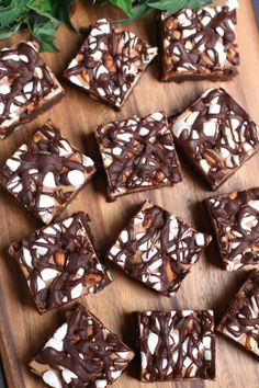 there are many pieces of brownie on the cutting board with chocolate and nuts all over it