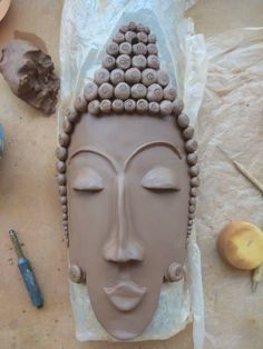 a clay face is sitting on the table next to some other tools and materials that are around it