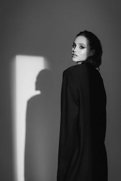 a woman standing in front of a shadow on the wall