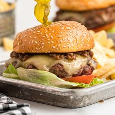 a cheeseburger with lettuce and tomato being drizzled over it