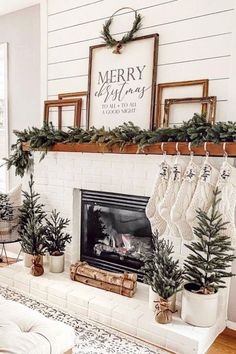 a fireplace decorated for christmas with stockings hanging from the mantel and potted trees