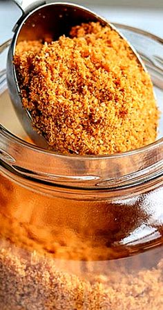 a spoon with some food in it on top of a glass jar filled with liquid