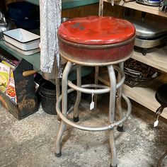 a red stool sitting on top of a metal counter